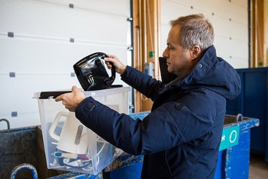 man putting old electronics into recycling bins.