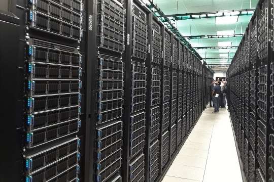 group of people standing in a row of hundreds of computer servers.
