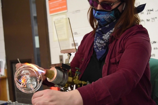 artist rotating a glass ball throw a flame.