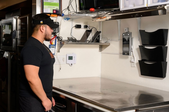 an employee at a Subway resaurant getting his face scanned.