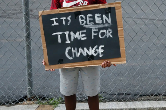 person holding a sign that reads: It's been time for change.