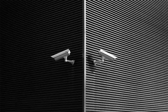 corner of a building with a security camera pointed in opposite directions on each wall.