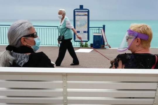 two people sitting on a bench talking.