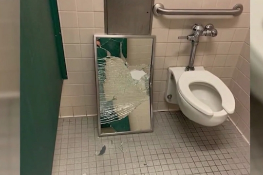 broken mirror on the floor of a school bathroom.