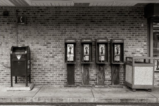 black-and-white bank of payphones outside a convenience store.