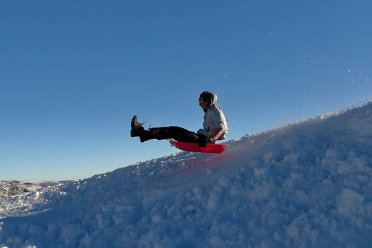 person sledding down a snowy slope.