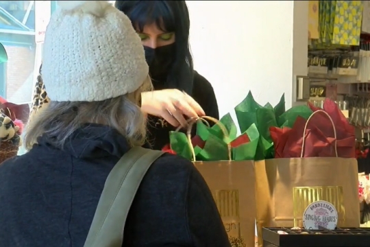 cashier bagging customer's times with green and red tissue paper.