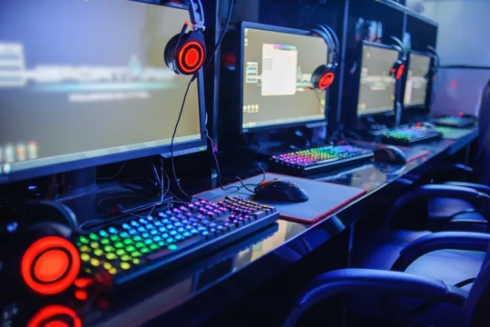 computer gaming consoles with monitors, keyboards and headsets.