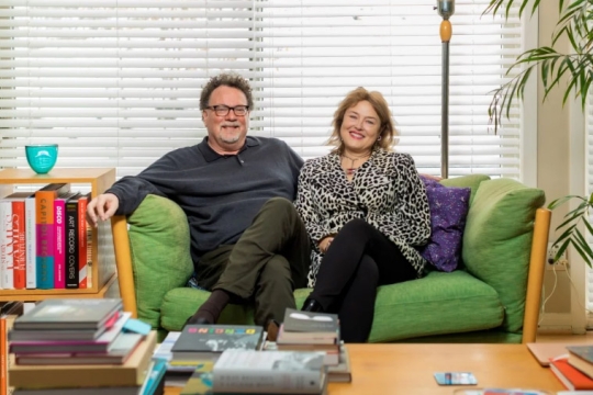 two authors sitting on a green couch.
