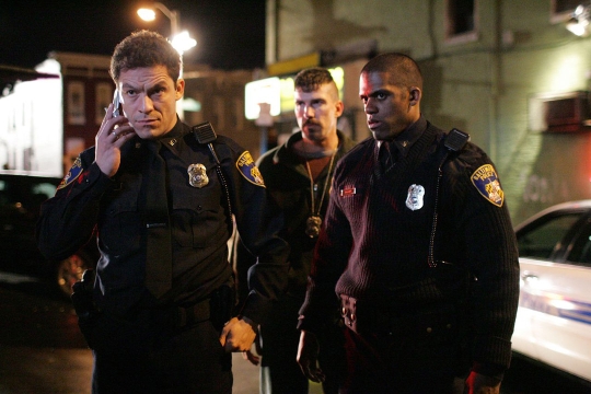 scene from the TV show The Wire with three police officers standing outside.