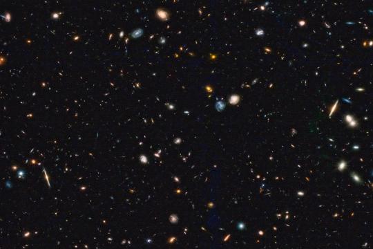 image from a space telescope showing specks and blobs of differing sizes and colors.