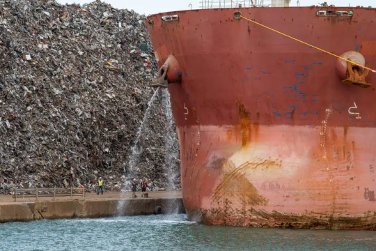 cargo ship at a port dumping out its ballast water.