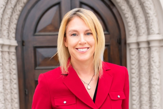 Blonde woman smiling wearing red coat.