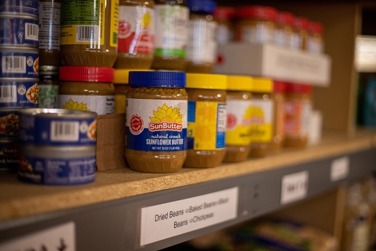 shelf with peanut butter jars and cans of tuna fish.