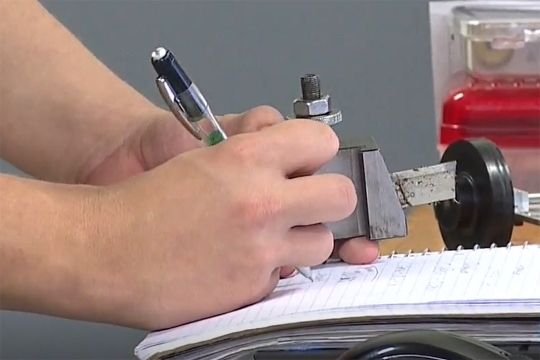 person holding a gauge and writing in a notebook.