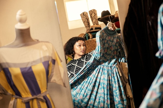woman holding up a dress by a hanger. 