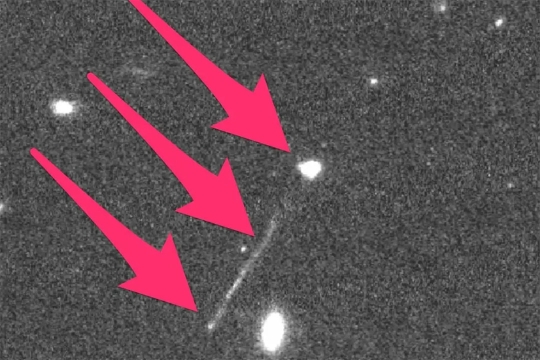 image of space with three red arrows pointing to a black hole and a trail of stars.