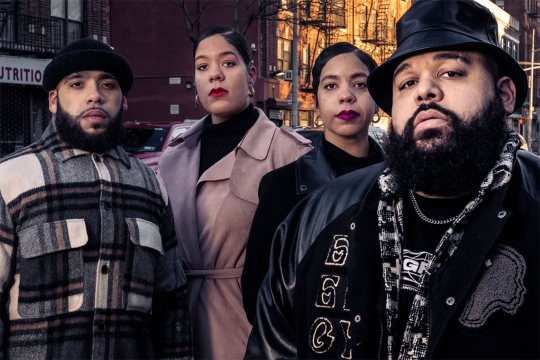 four people standing together on a city street.