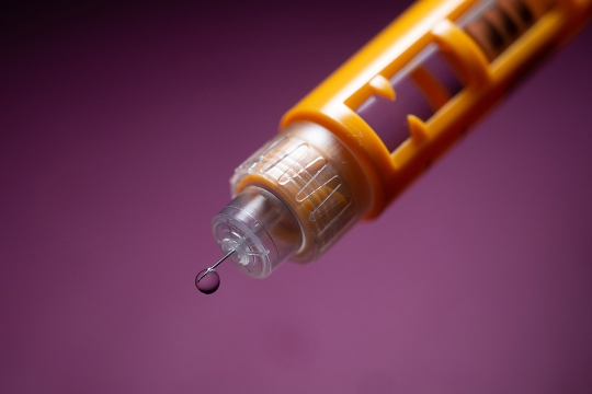 close-up of a needle for dispensing insulin with a drop of liquid at the tip.