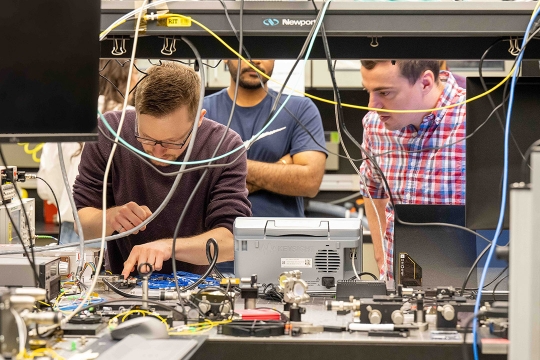 three men working in an electronics lab.