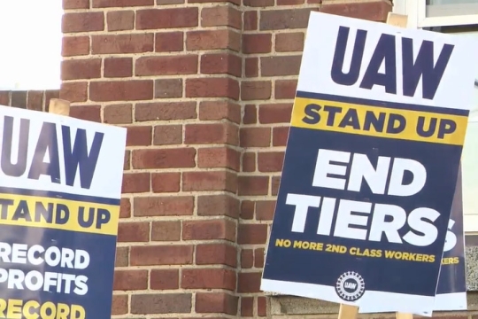 picketing signs that read U A W stand up, end tiers, no more second class workers.