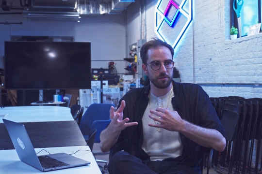 Man with glasses sitting at desk with computer.