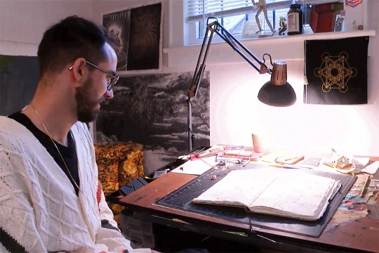 artist looking at a sketch pad on a messy desk.