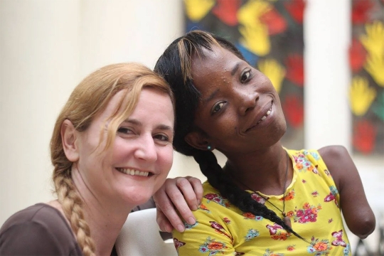 a white female scientist posing next to a Haitian woman.