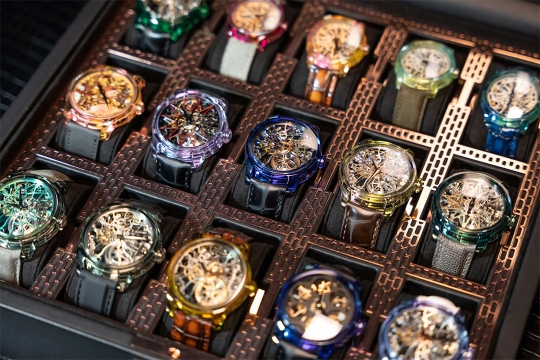 fifteen luxury wrist watches in a case, with colorful and intricate faces.