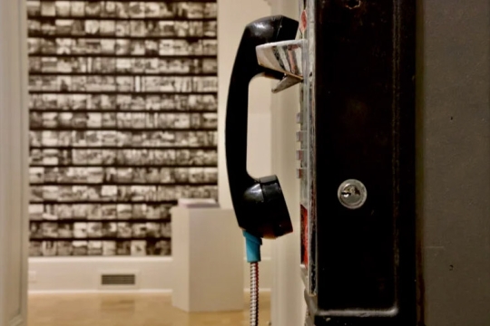 a sideview of a payphone in a museum like room.
