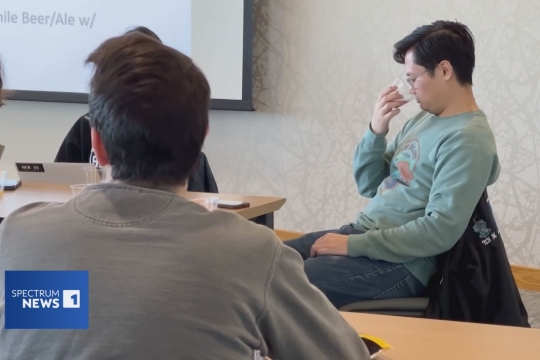 a student sits in a classroom smelling the aroma of a beer in the Beers of the World class