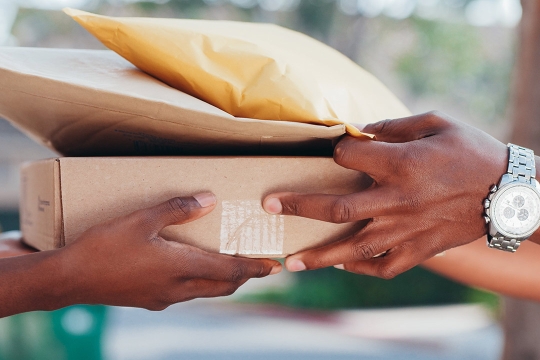 a person Handing Out a Brown Box and Envelopes to a Person