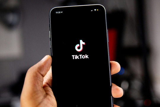 a hand holding a phone with the tiktok logo.