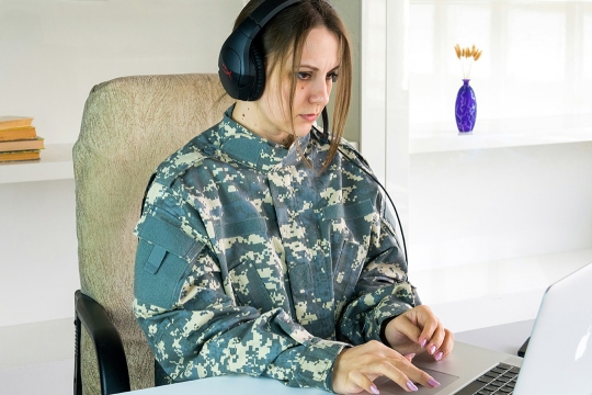 Attentive female soldier student working on laptop pc.