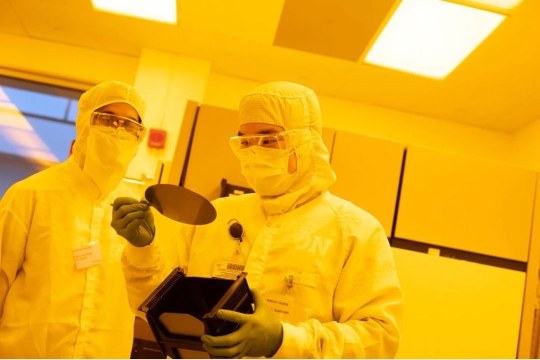 Two people work in a lab with yellow lighting