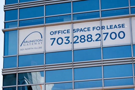 a for lease sign appears covering windows of a high rise building in a metropolitan area.