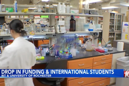 a person in a white lab coat works at a counter in a lab setting.