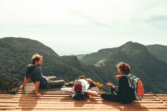 three people relax on a deck in the mountains