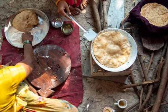 a variety of traditional indian foods, like naan bread, are shown in pans from above.