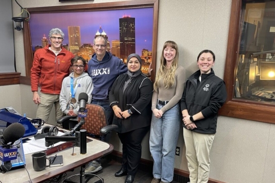a group of people stand in a radio studio