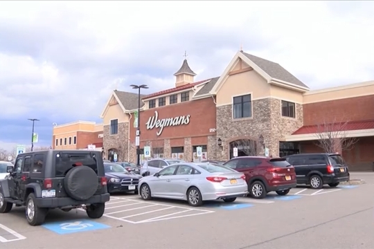 The outside of a Wegmans grocery store with vehicles in the parking lot