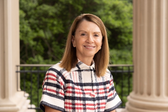 a woman in a plaid tweed top sits in an outdoor patio