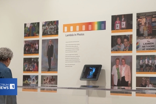an older person looks at photos on a wall in a gallery