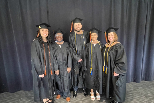 five physicians in graduation regalia