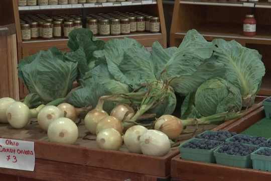 onions sit on a wooden display in a grocery store