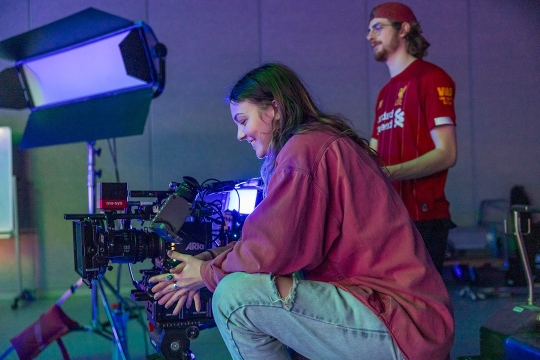 two students work behind a camera in a film studio