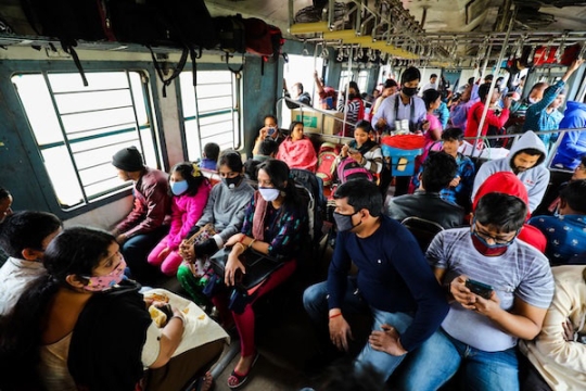 large amounts of people crowd on to a bus in india