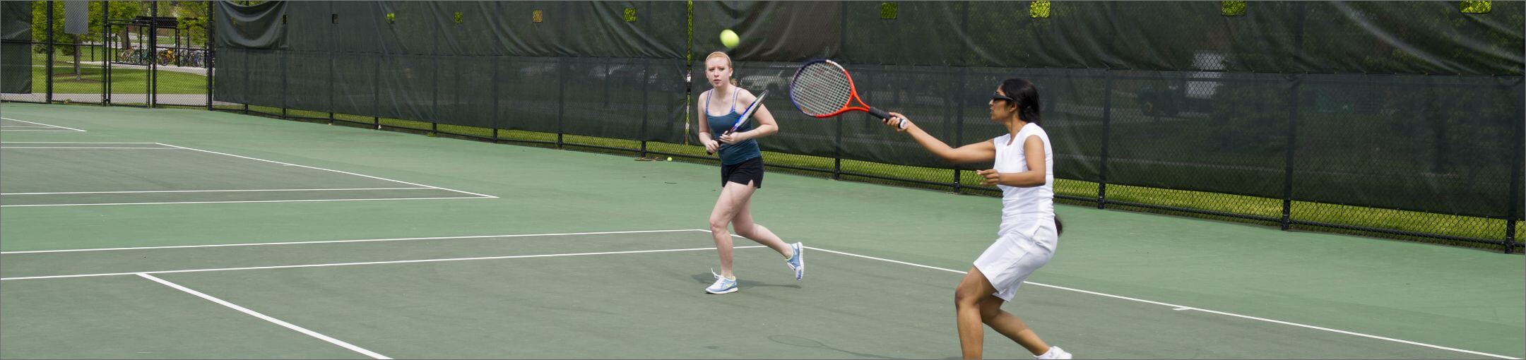 Students playing doubles tennis.