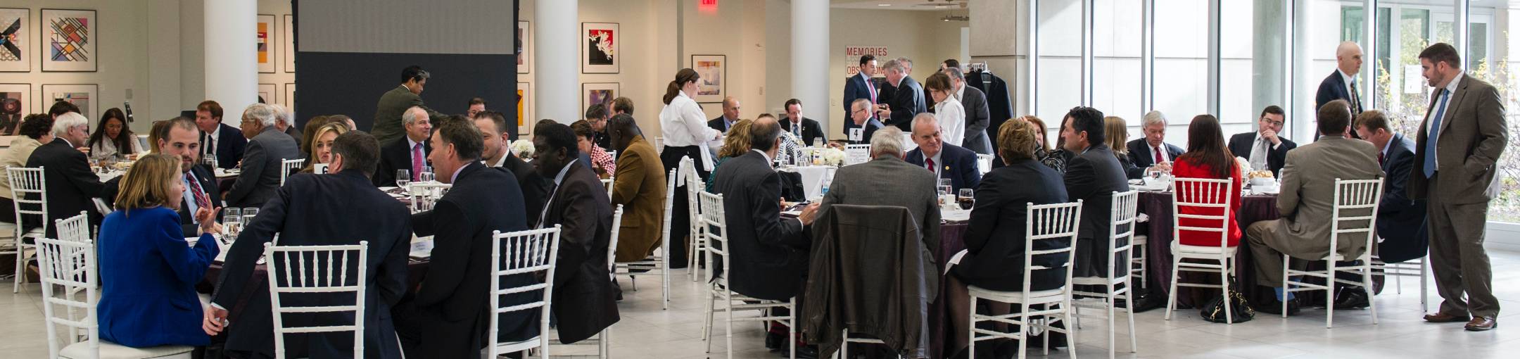 People sitting around white tables in a party room