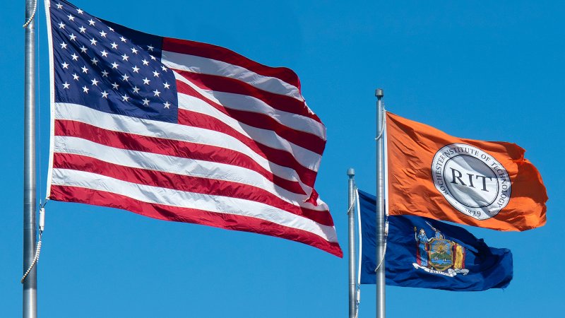American, RIT, and NYS flag blowing in the wind